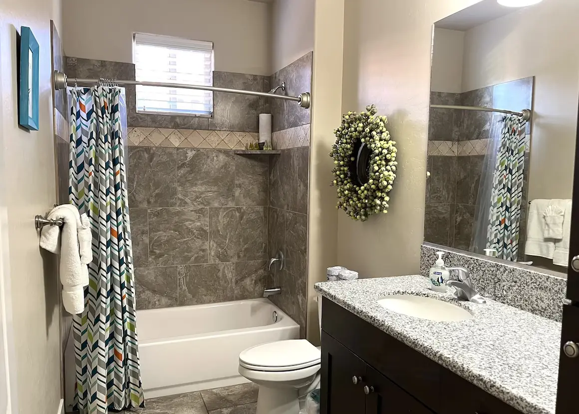 Hall bathroom with a tub and shower and granite vanity