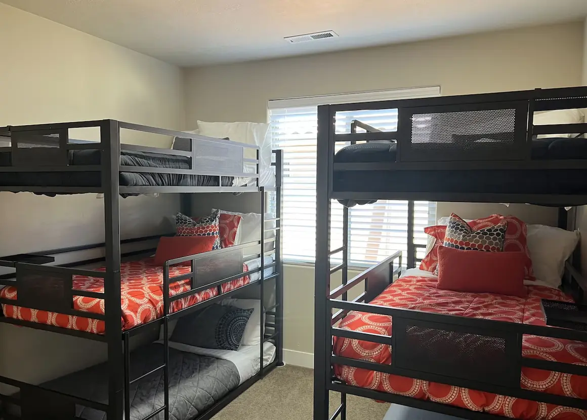 Bunk room with two black metal triple bunk beds and coral bedding