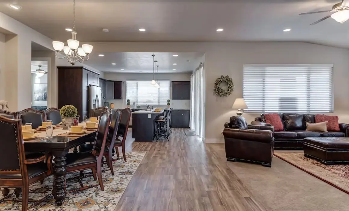 Open great room with a dining table for ten, leather sofas and the kitchen beyond
