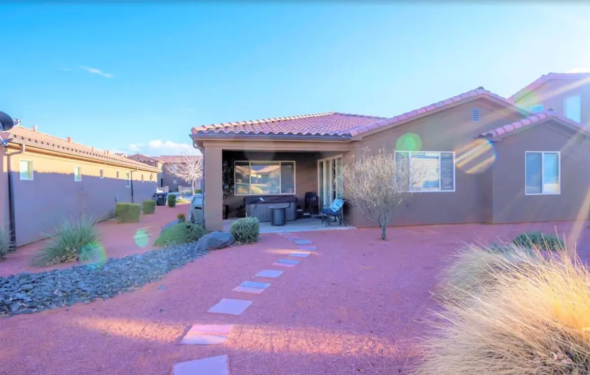 Back of the house at golden hour, with a stepping-stone path across red gravel to the patio