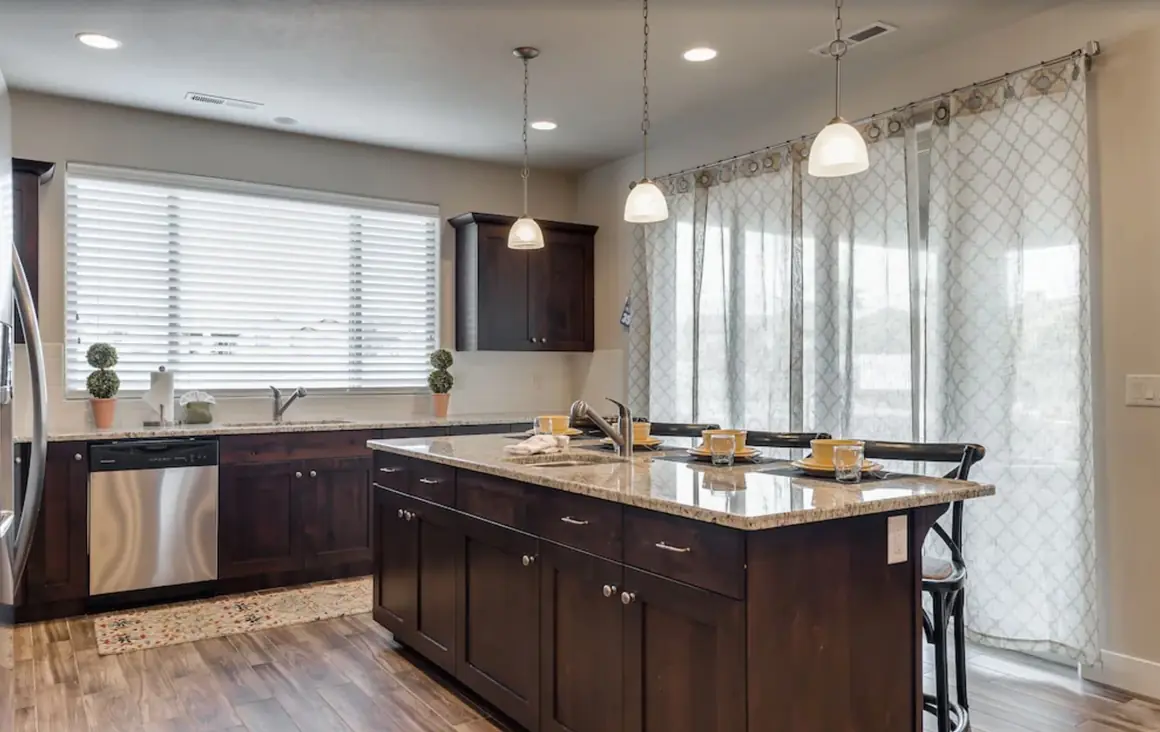 Kitchen island with pendant lights and sheer curtains on the patio door