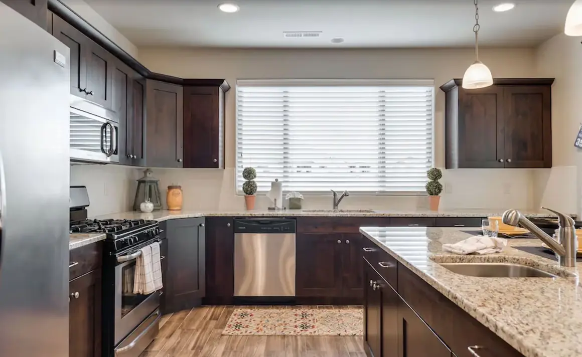 Kitchen sink under a bright window, with the gas range to the left