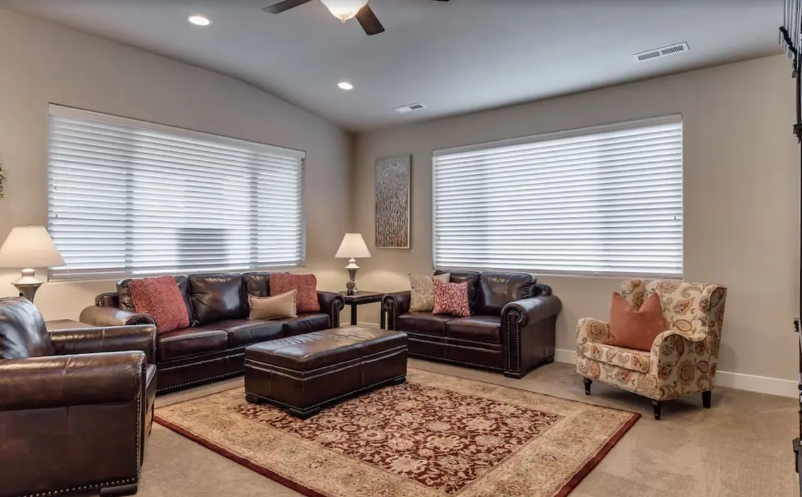 Living room with two leather sofas, an armchair and an ottoman on a red rug