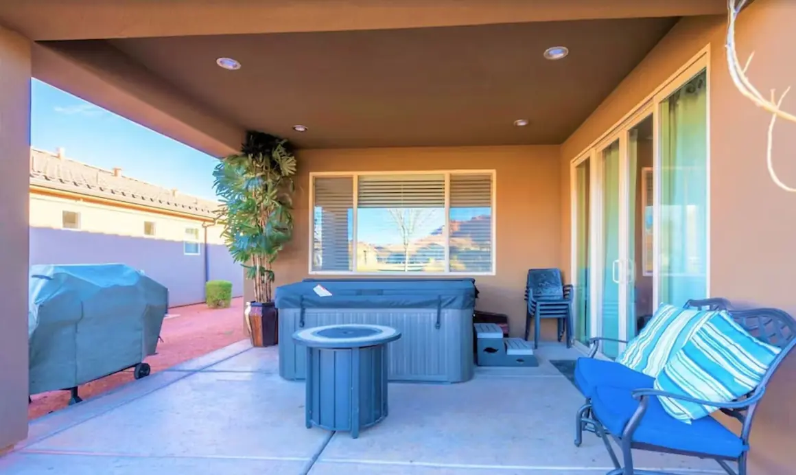 Covered back patio with a private hot tub, fire pit table and glider bench