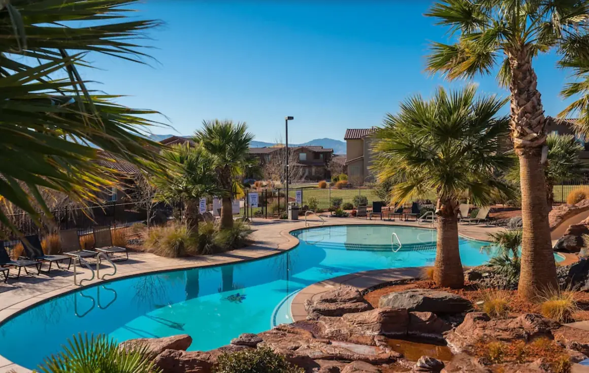 Palm trees and red rock around the Paradise Falls resort pool on a clear day